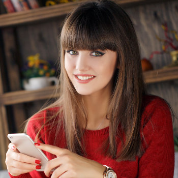 Girl reading SMS on mobile phone Elegant Smiles care