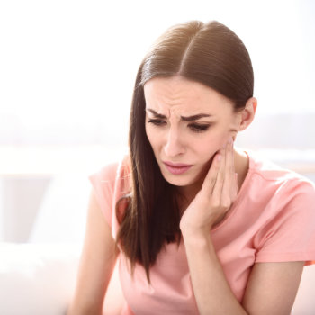 Brunette woman holding cheek tooth pain Emergency Dental Care Roswell