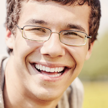 Young man with glasses smiling Elegant Smiles patient